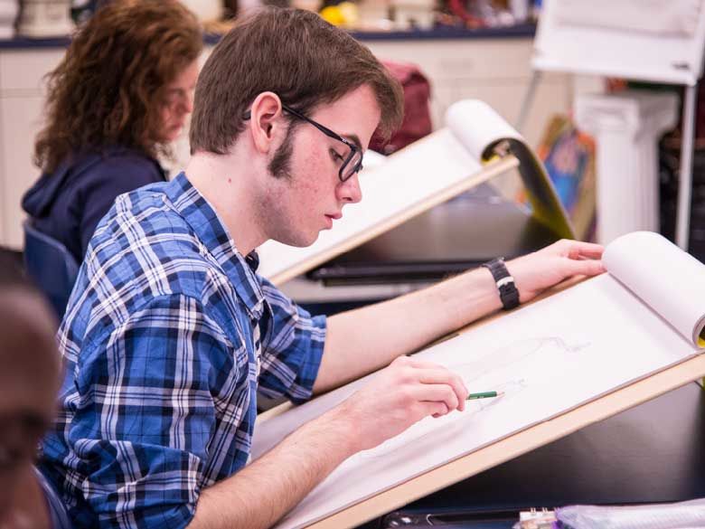A student draws in a sketchbook.